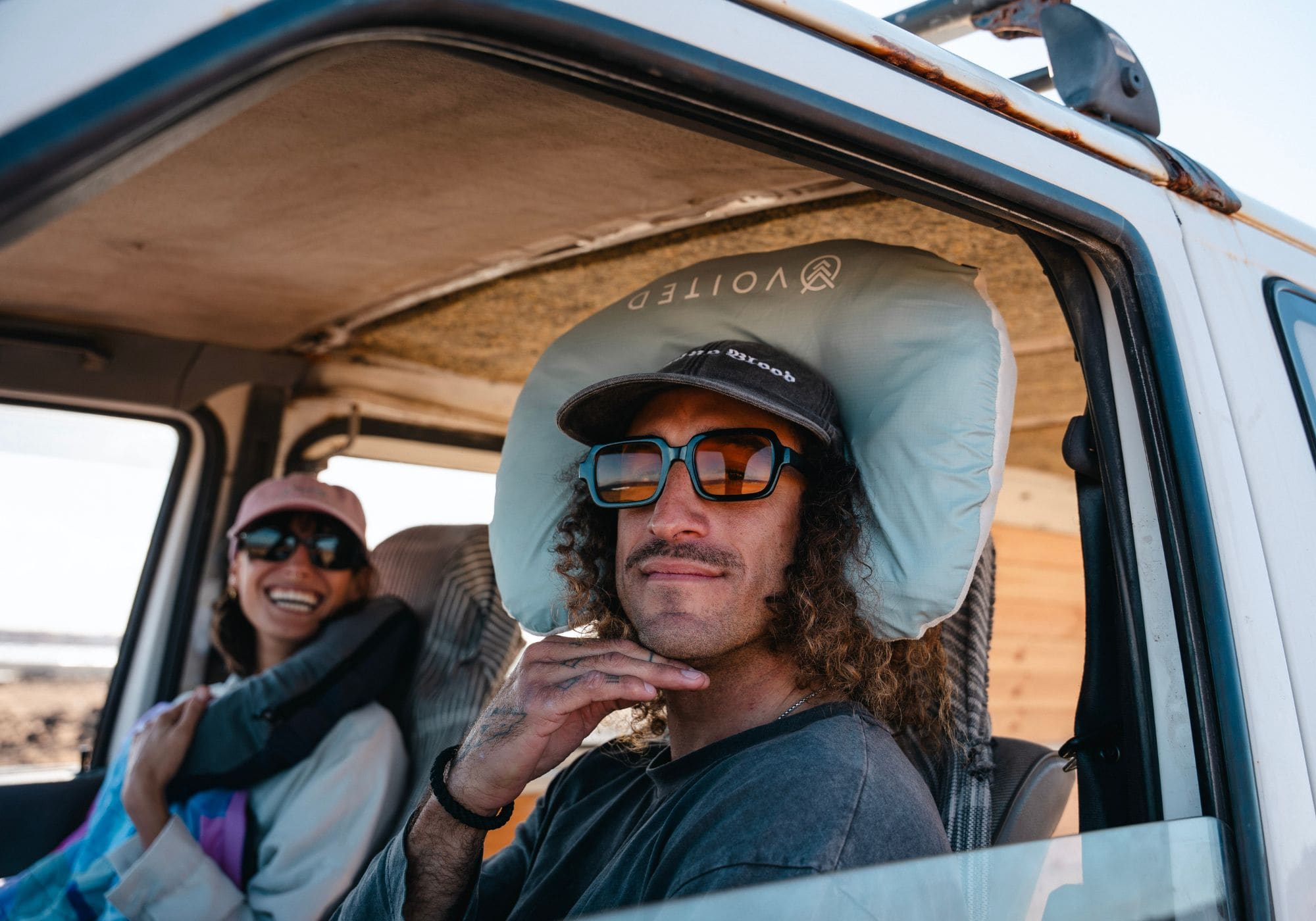 Homme portant l'oreiller de voyage VOITED NeckPack dans un van, avec une passagère souriante