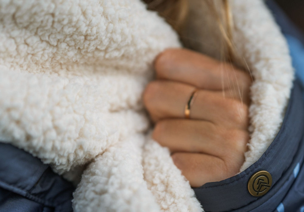 Gros plan d'une main tenant le sherpa crème d'une couverture VOITED Cloudtouch.