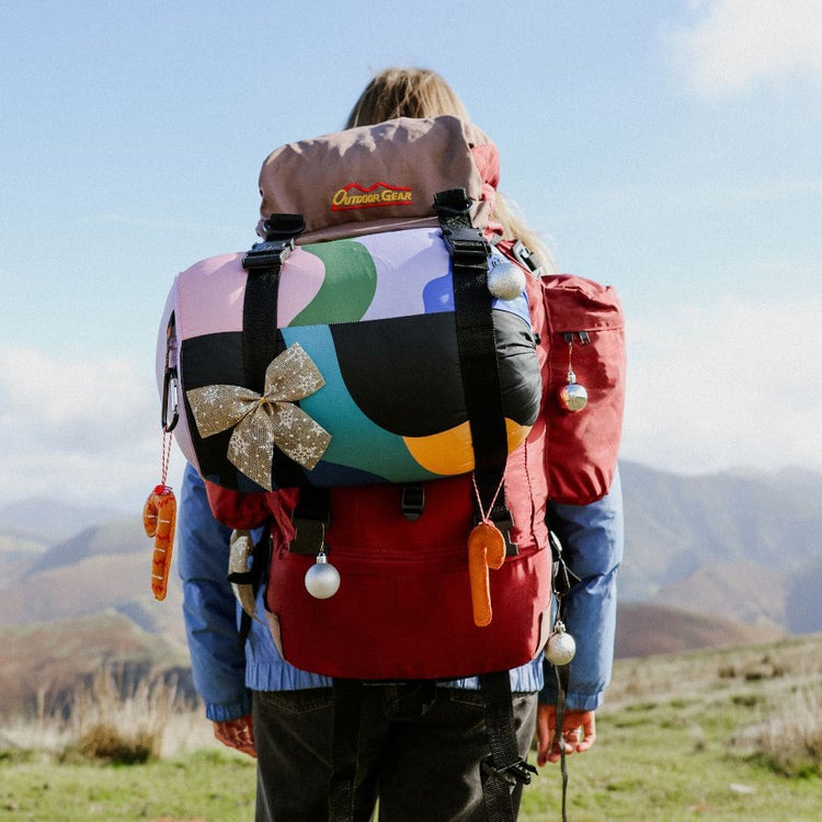 Randonneuse en montagne avec une couverture VOITED Cloudtouch colorée sur un sac à dos décoré pour Noël.