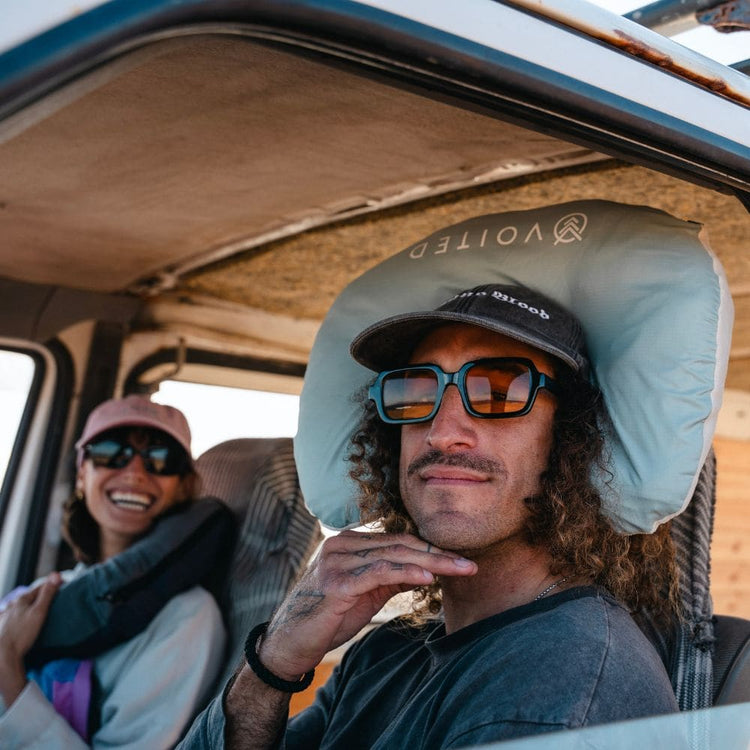 Homme portant l'oreiller de voyage VOITED NeckPack dans un van, avec une passagère souriante